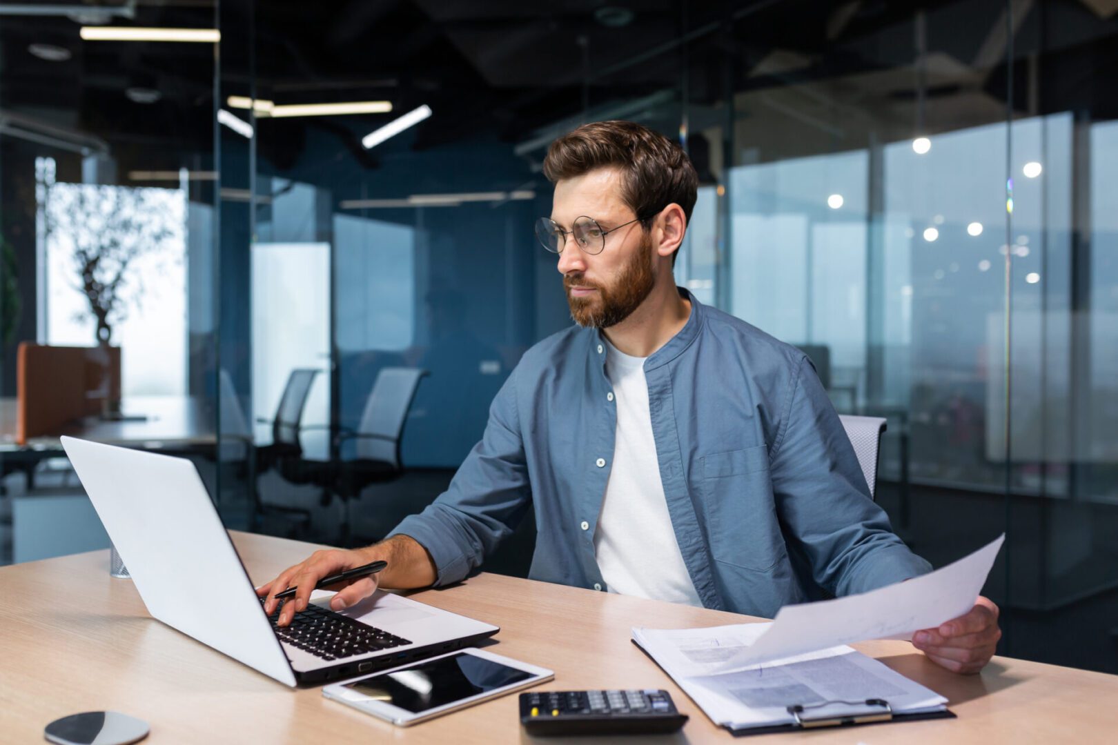 Man working on laptop with documents.